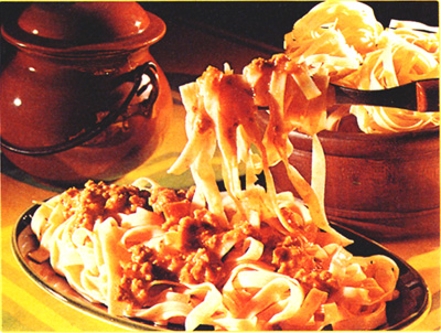 Pasta being swirled onto a serving fork, with the ragu sauces